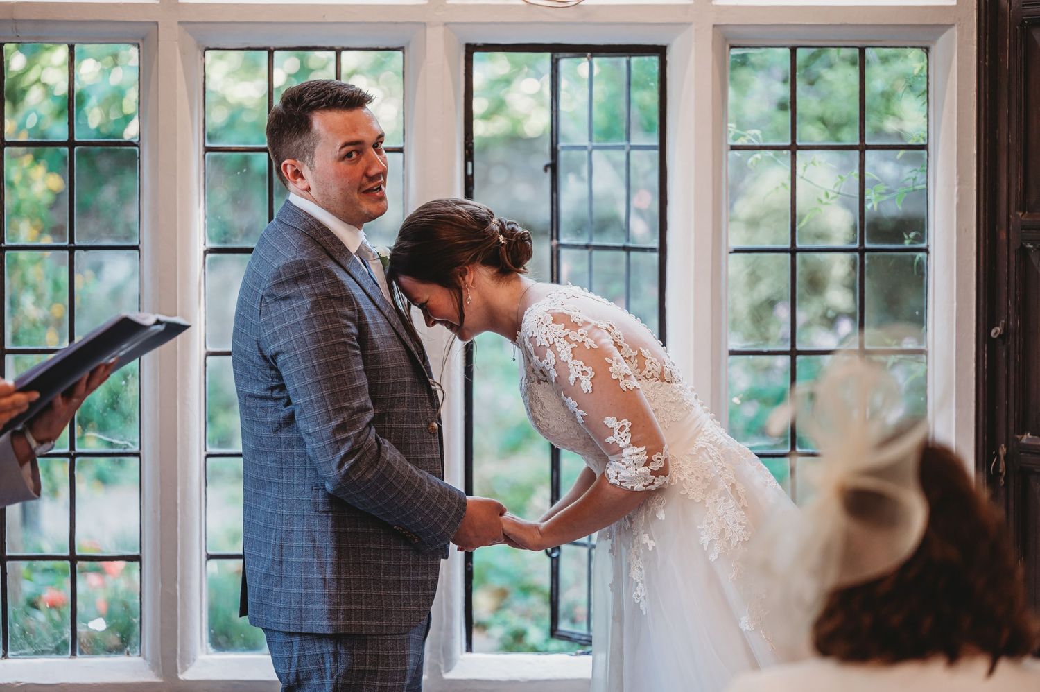 A romantic wedding moment captured in front of a bright window with natural light streaming in.