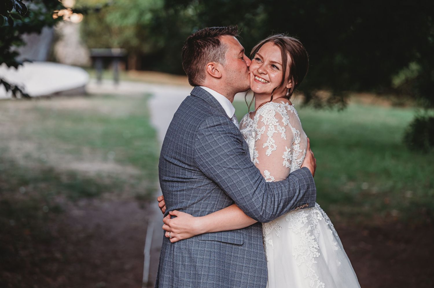 A joyful romantic moment captured outdoors between people in wedding attire embracing and smiling.