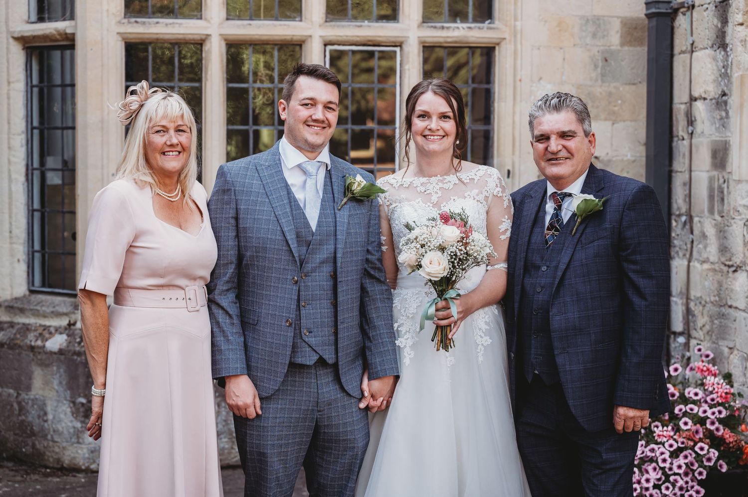 Wedding party poses together outside a historic stone church on a sunny afternoon.