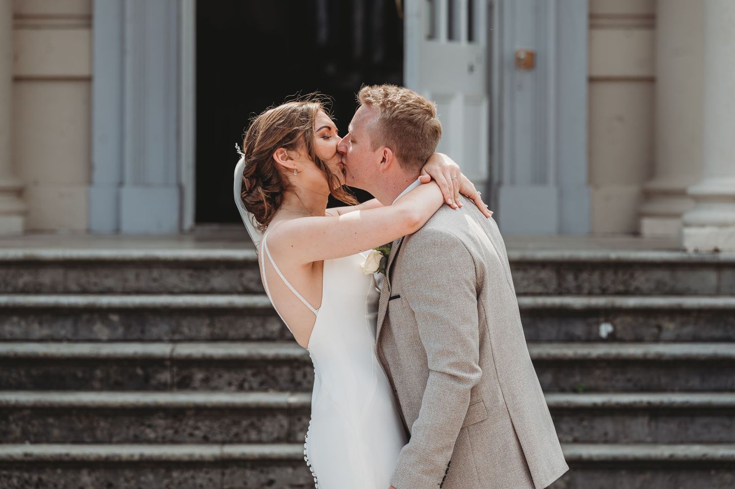 An intimate wedding moment captured on stone steps of a grand building.