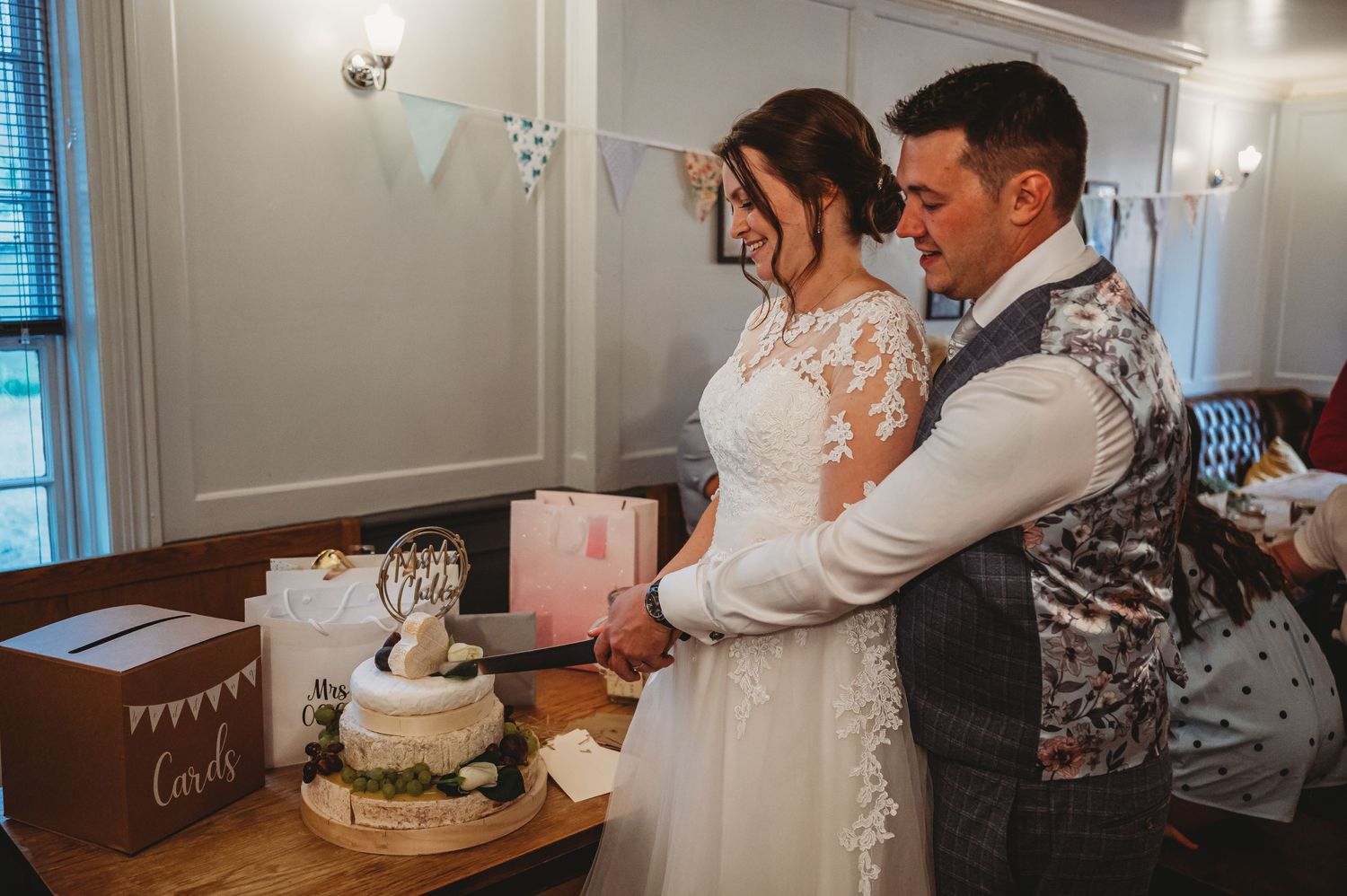 A bride and groom cut their rustic wedding cake together at their reception celebration.