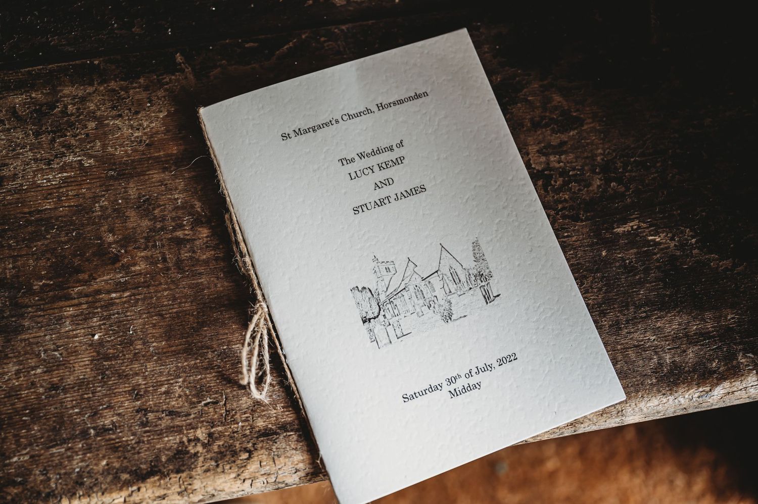 A gray notebook or script with sketched artwork lies on a dark wooden surface.