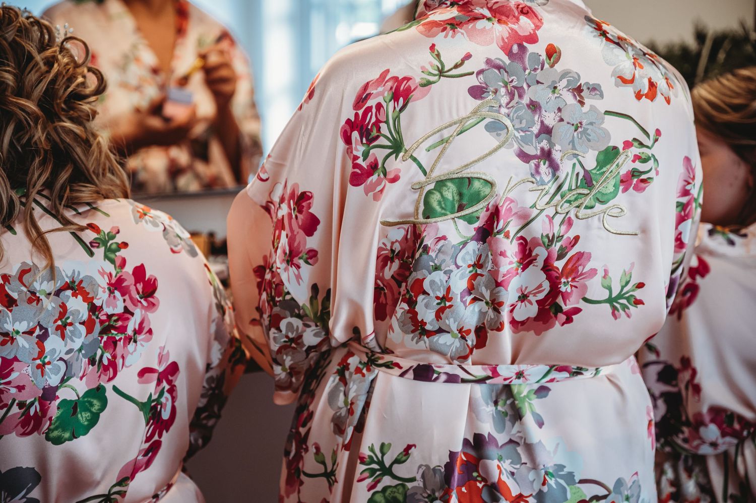 Floral satin robes with pink and green botanical patterns displayed against a soft blurred background.