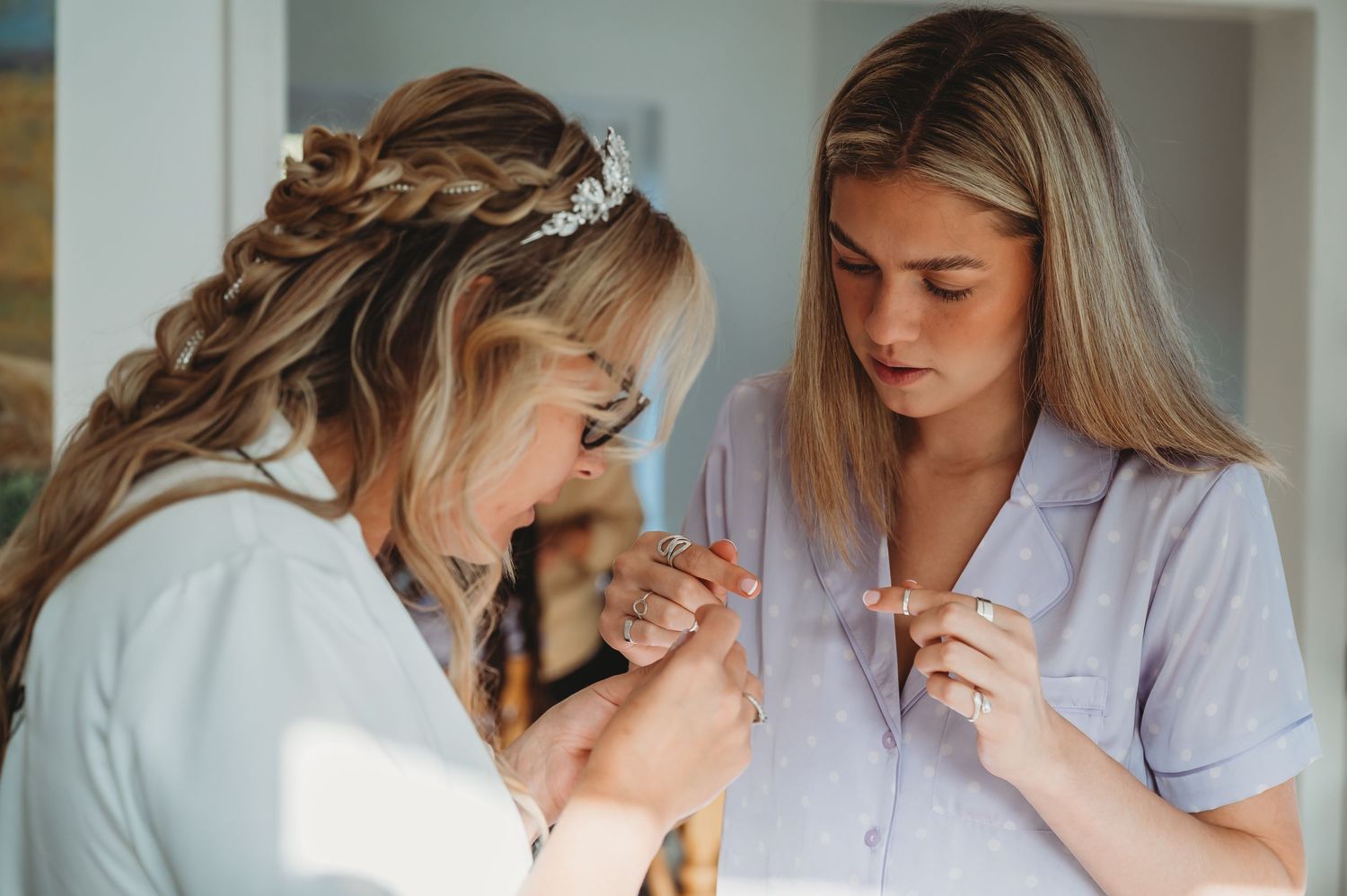 Two nurses in matching scrubs working together while looking down in a medical setting.