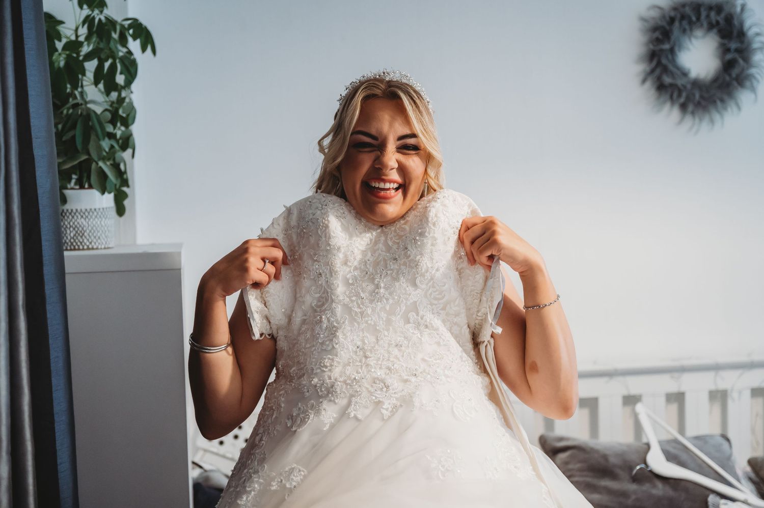 A joyful person in a flowing white dress poses with excitement while showing off elegant lace detail.