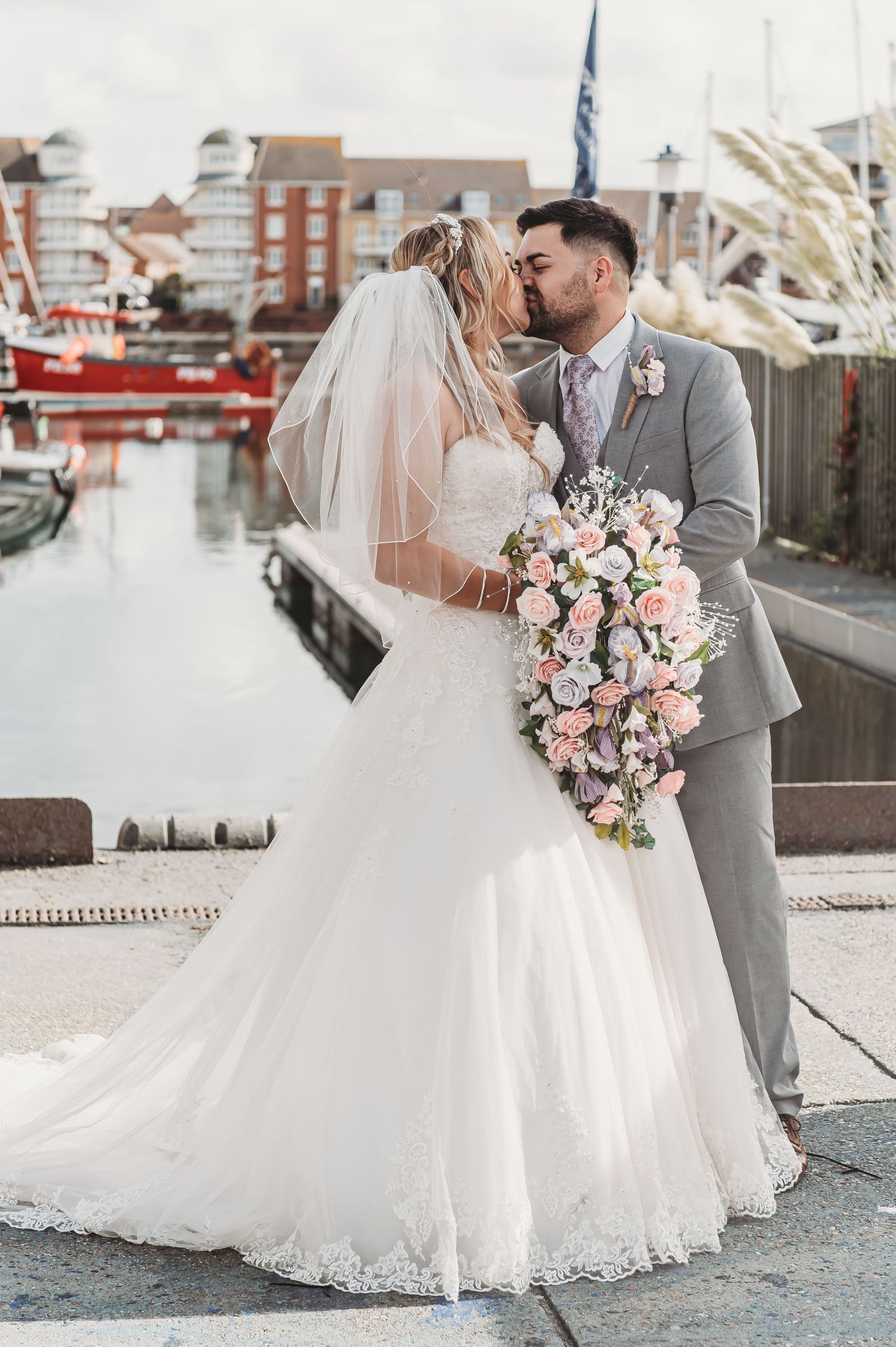 Seaside wedding portrait with elegant cascading floral bouquet and harbor views.