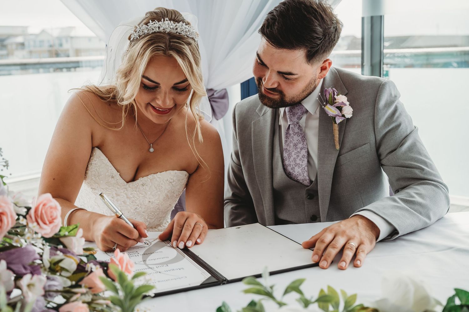 Newlyweds signing their marriage certificate at a modern waterfront venue.
