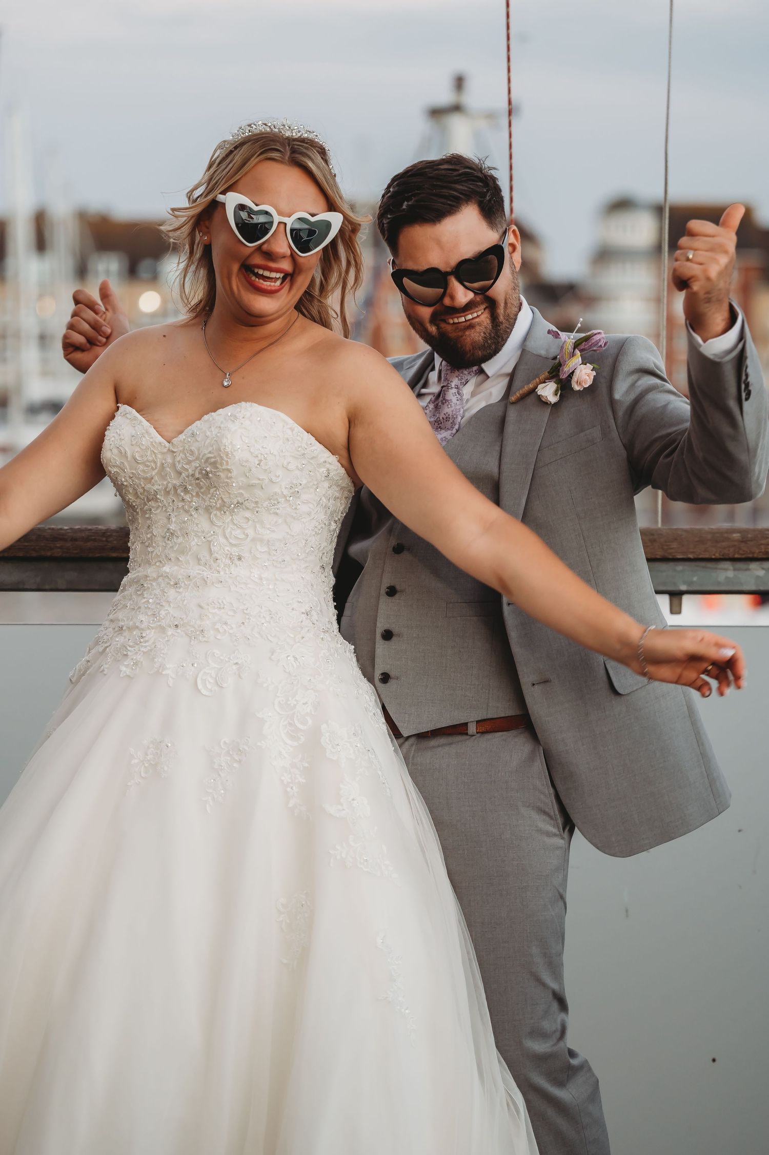 A fun wedding photo shows a couple in sunglasses posing playfully on a marina dock.