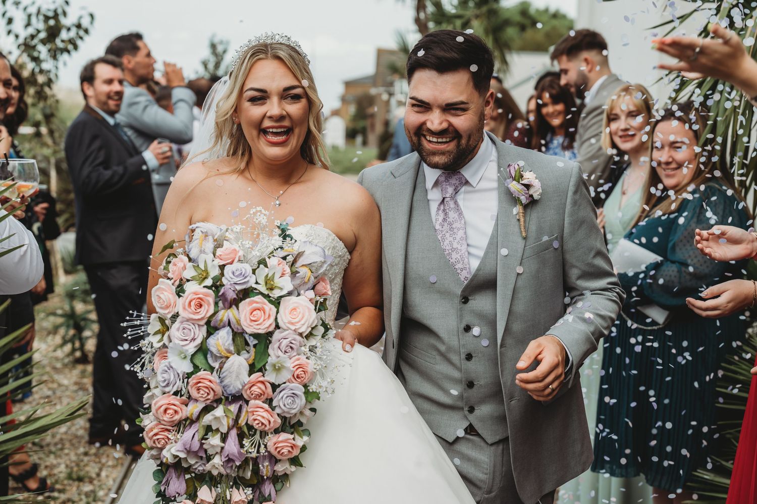 Happy couple celebrates during wedding recessional as guests shower them with confetti on their special day.