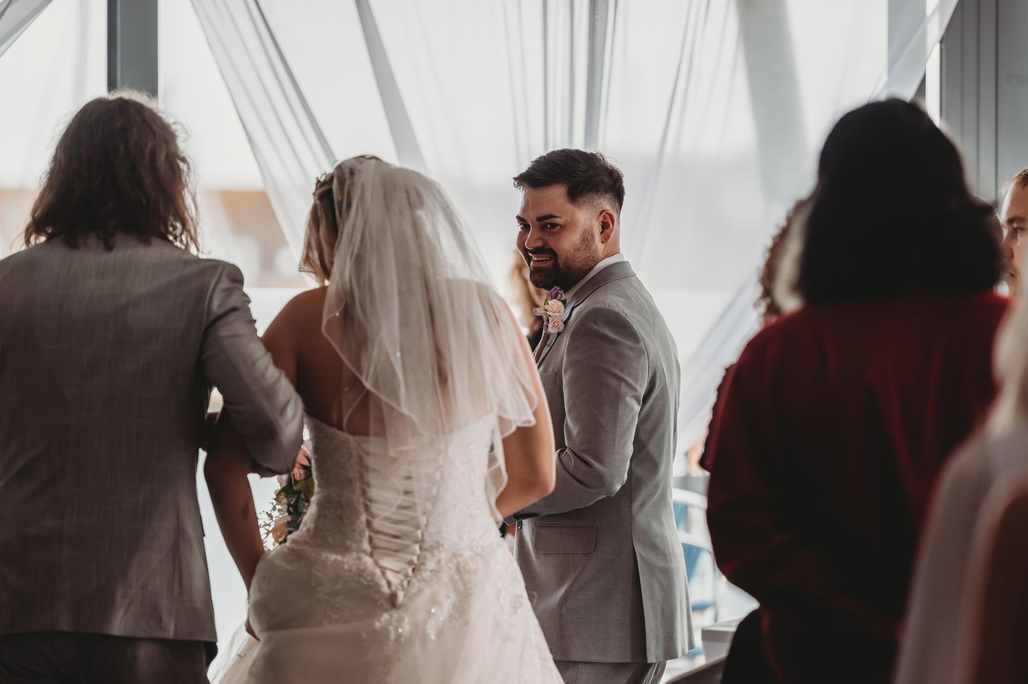 Intimate black and white wedding ceremony photo showing couple exchanging vows with guests and officiant.