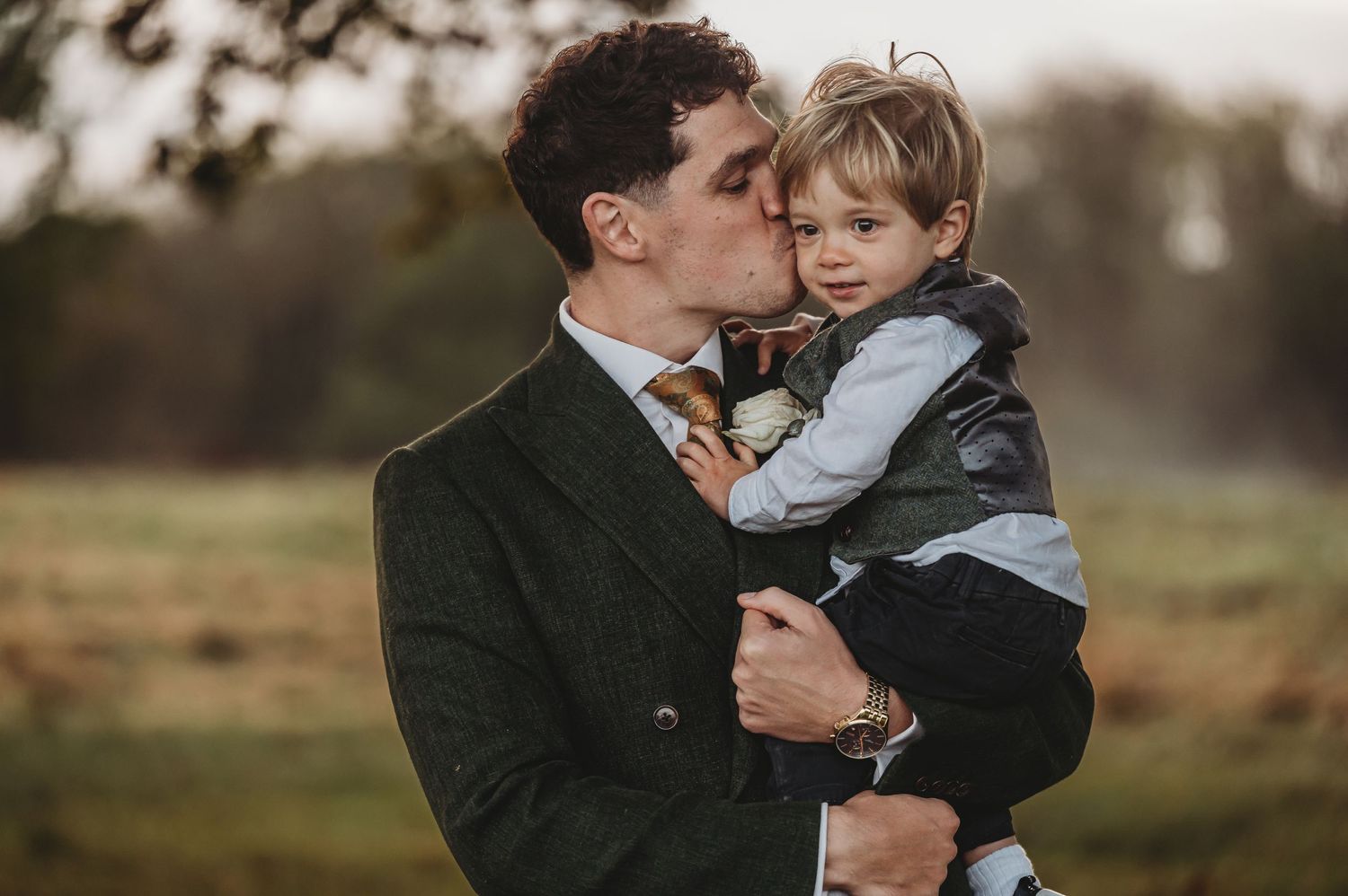 Tender outdoor portrait of father and young child sharing an intimate moment in autumn setting.