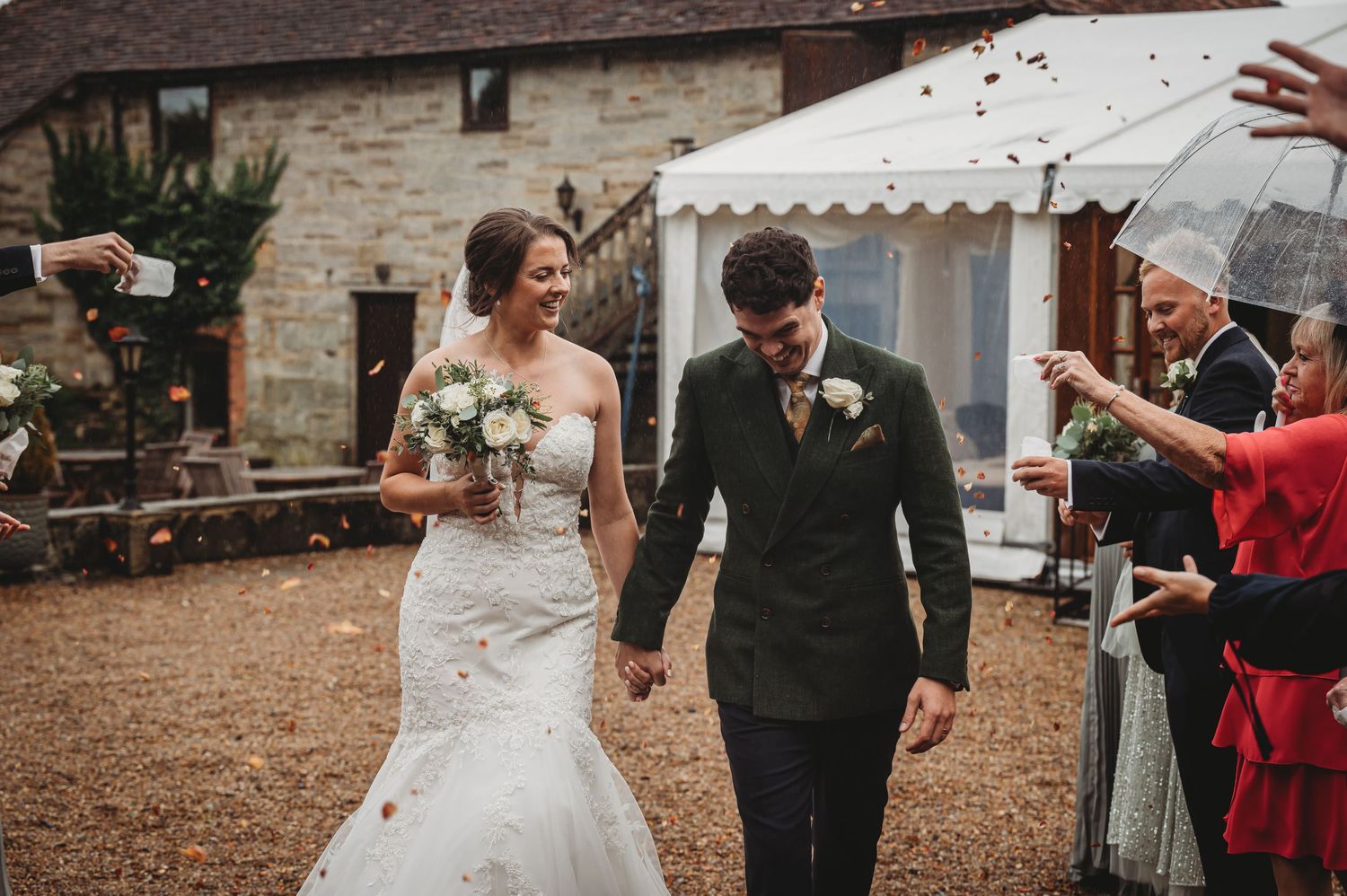 A happy couple walks hand in hand during their wedding celebration at a rustic venue.