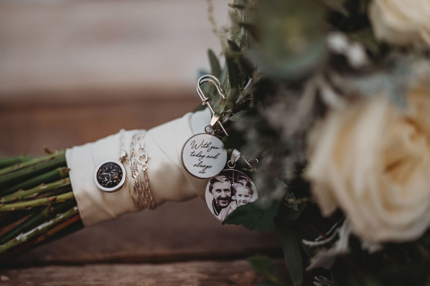 Wedding bouquet wrapped in white fabric with decorative medallion charms attached.
