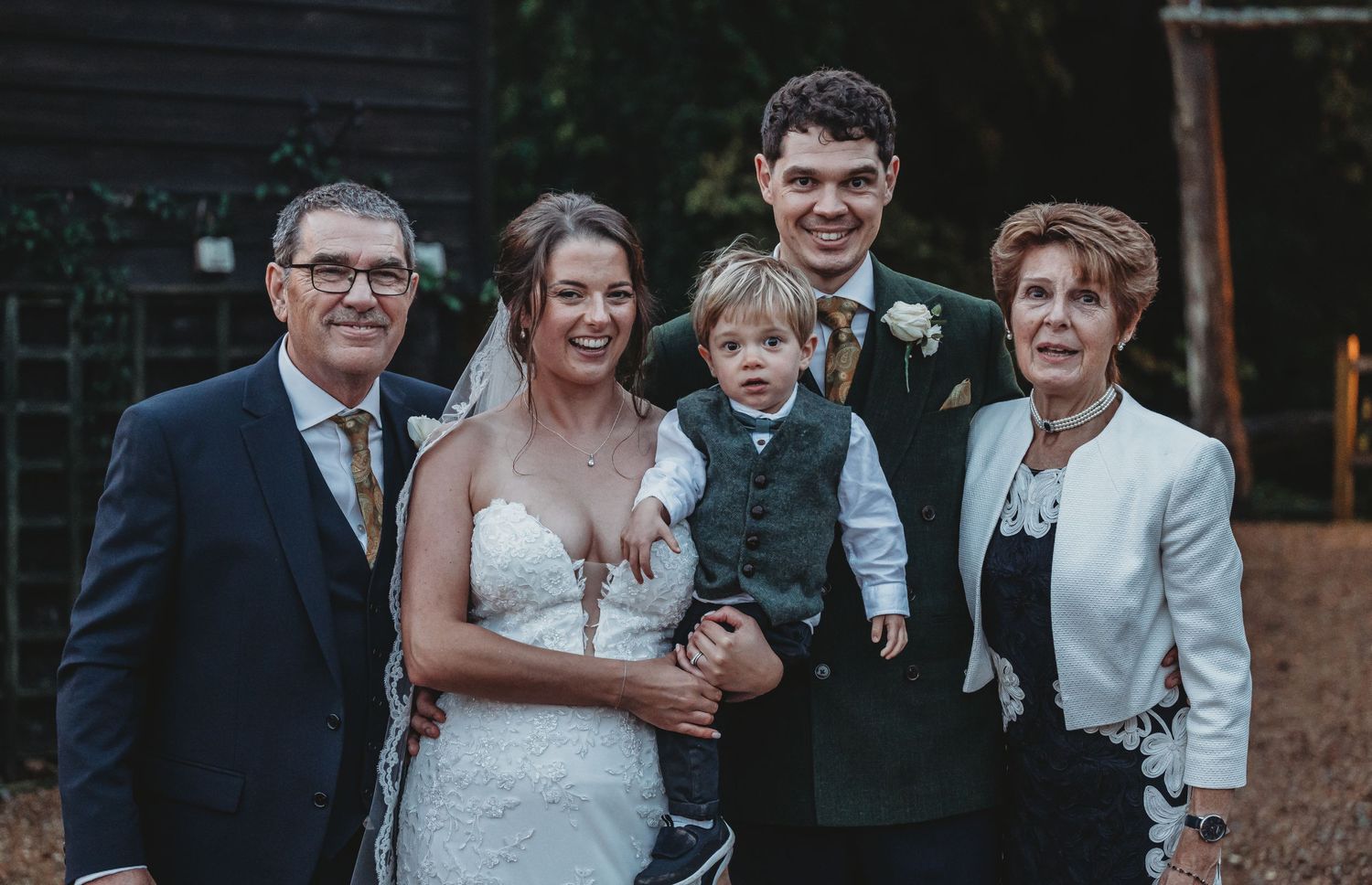 Family group photo at wedding reception with young child in formal attire.