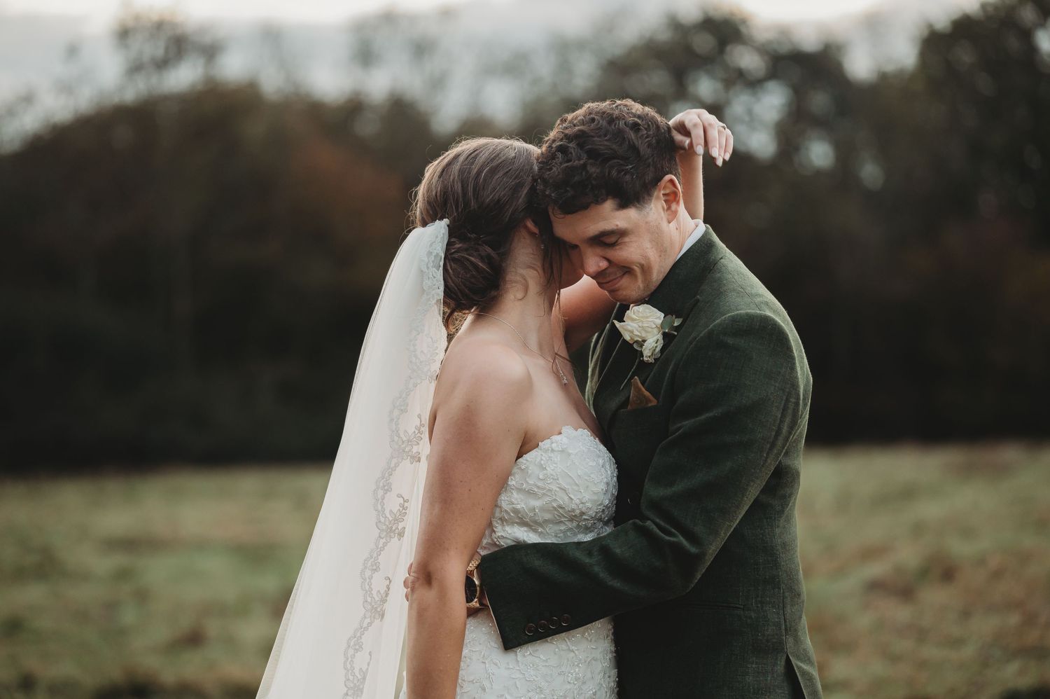 Intimate outdoor wedding portrait against a misty natural backdrop at dusk.