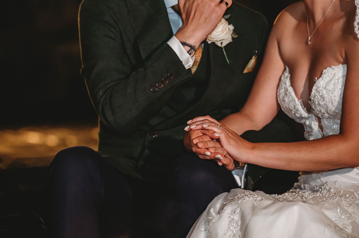 A person wiping tears with tissue sits beside someone wearing a lace wedding dress during an emotional moment.
