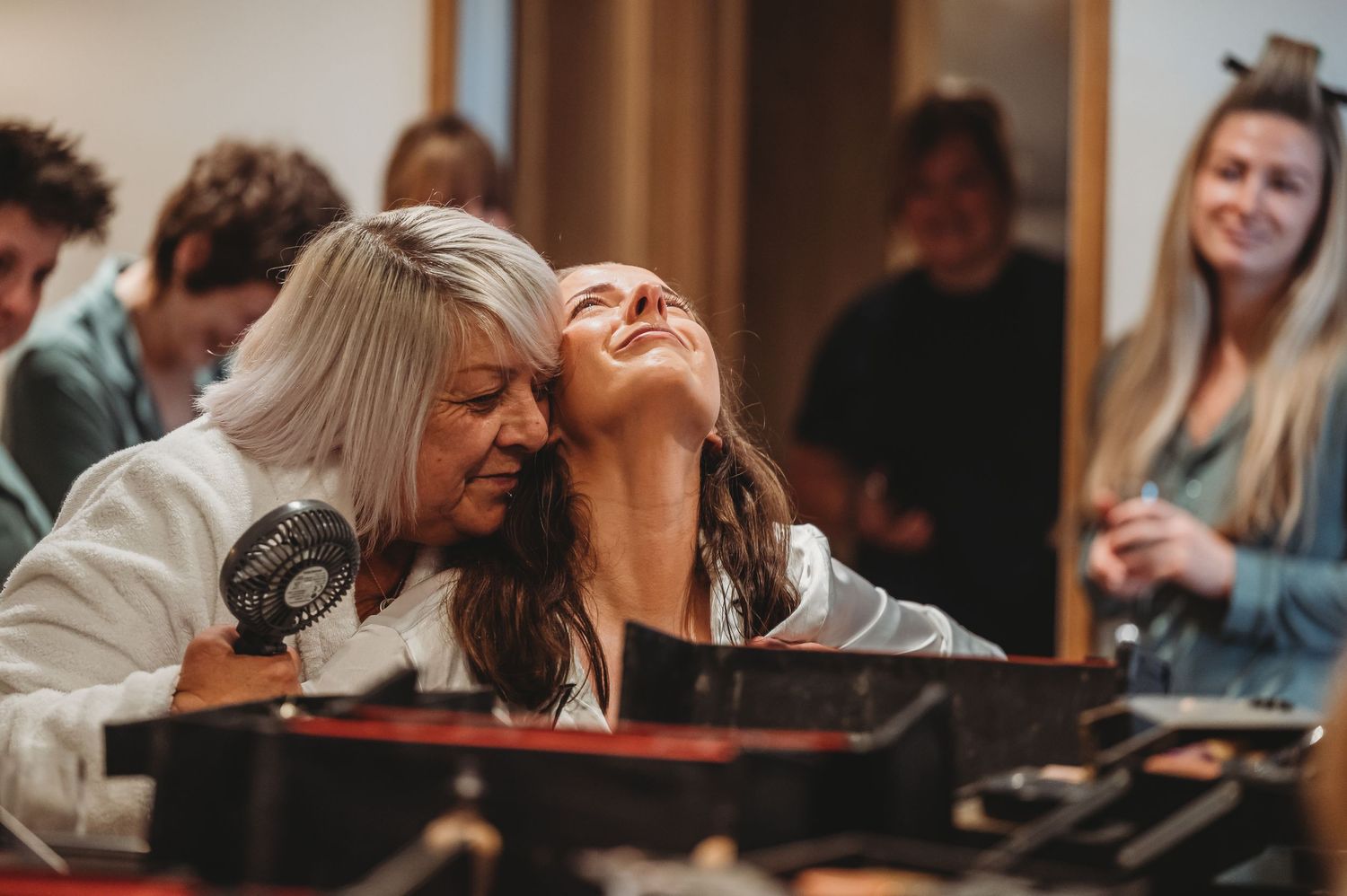 Two people laugh together while seated at a piano during what appears to be a music session or rehearsal.