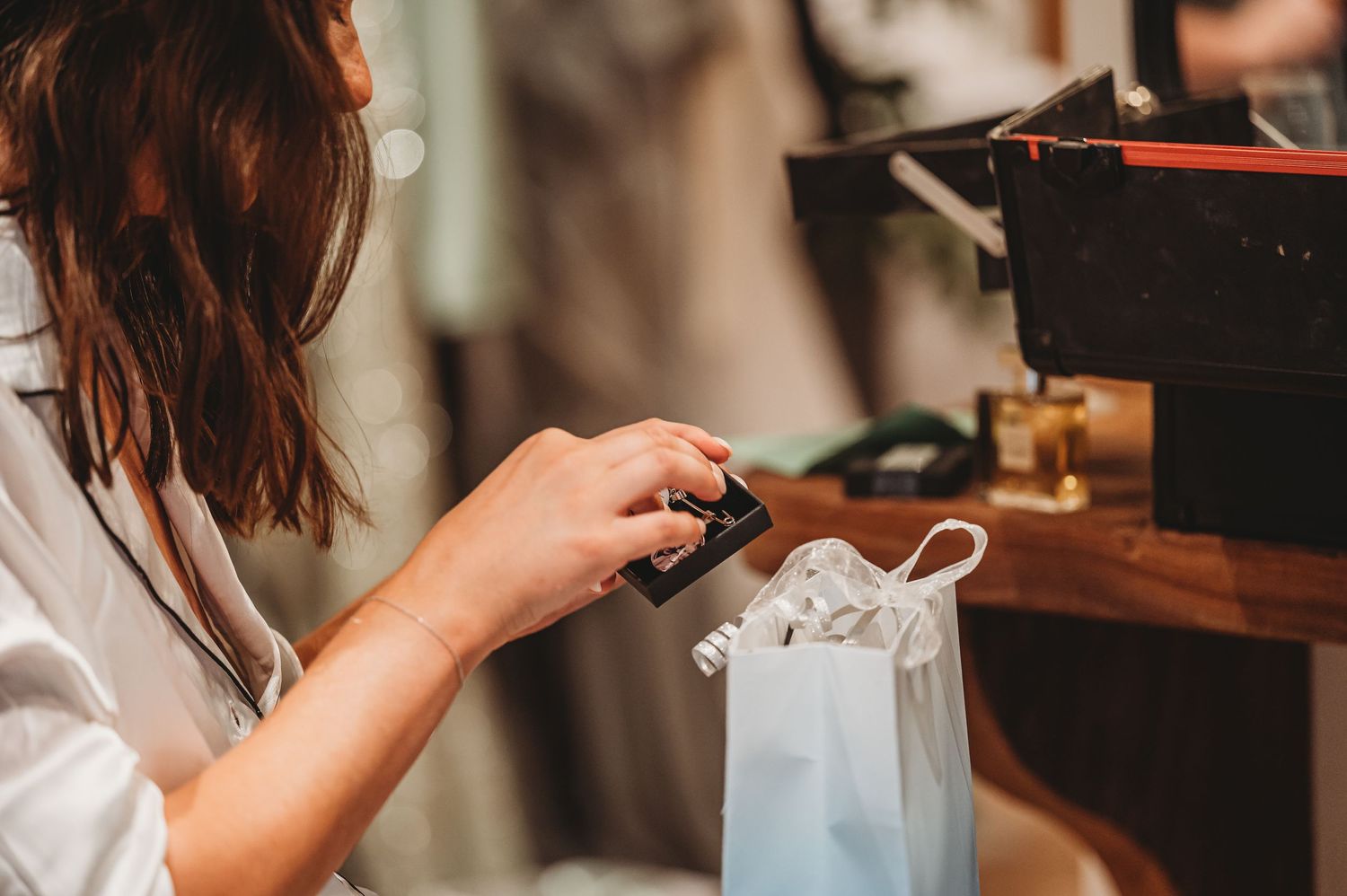 Hands preparing clothing items on hangers in a dressing room.