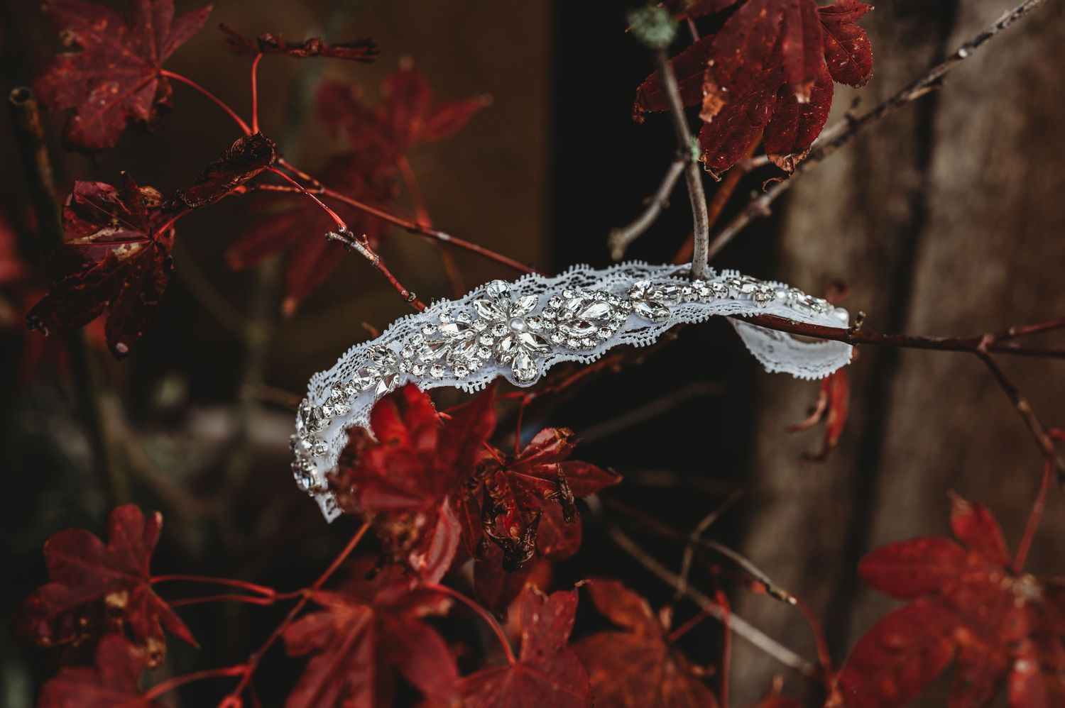 A lace white alligator ornament nestled among vibrant red autumn leaves in a dark moody setting.