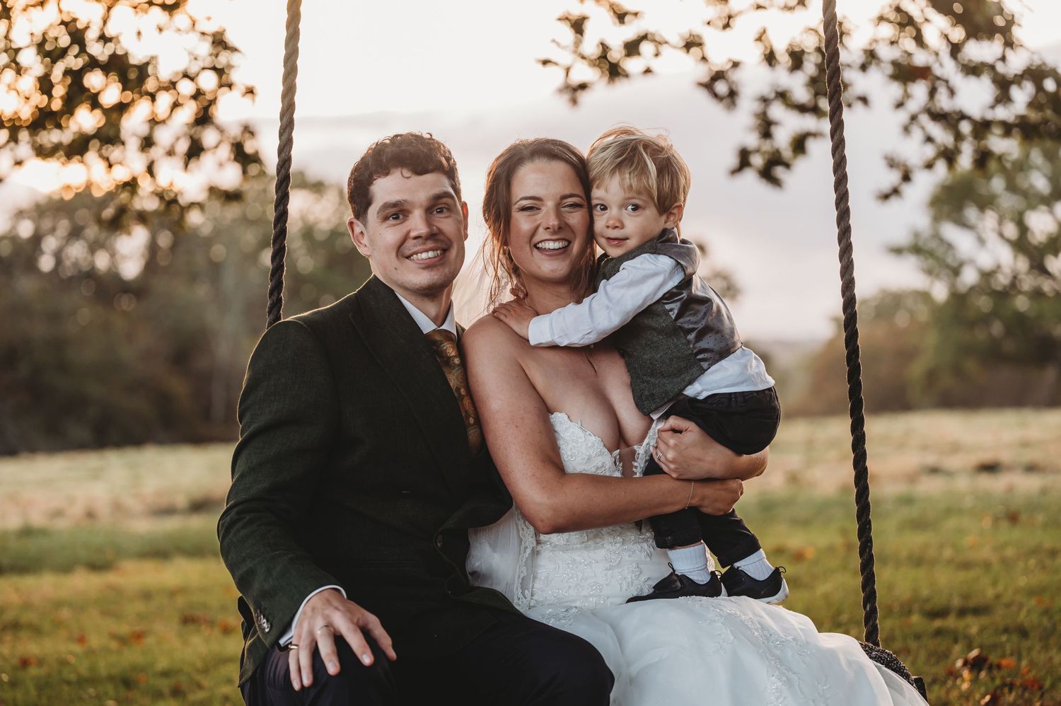 Wedding couple sitting on a swing in a rustic outdoor setting during golden hour.