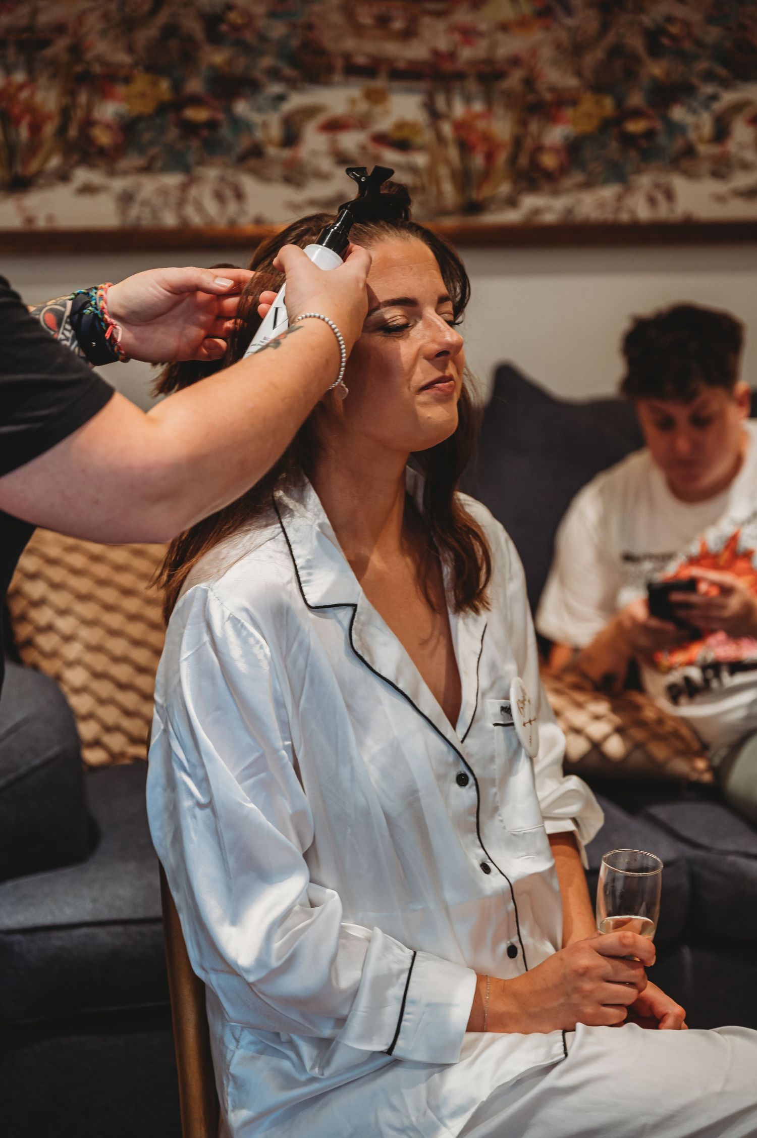 Getting ready scene with someone having makeup applied while wearing silk pajamas.