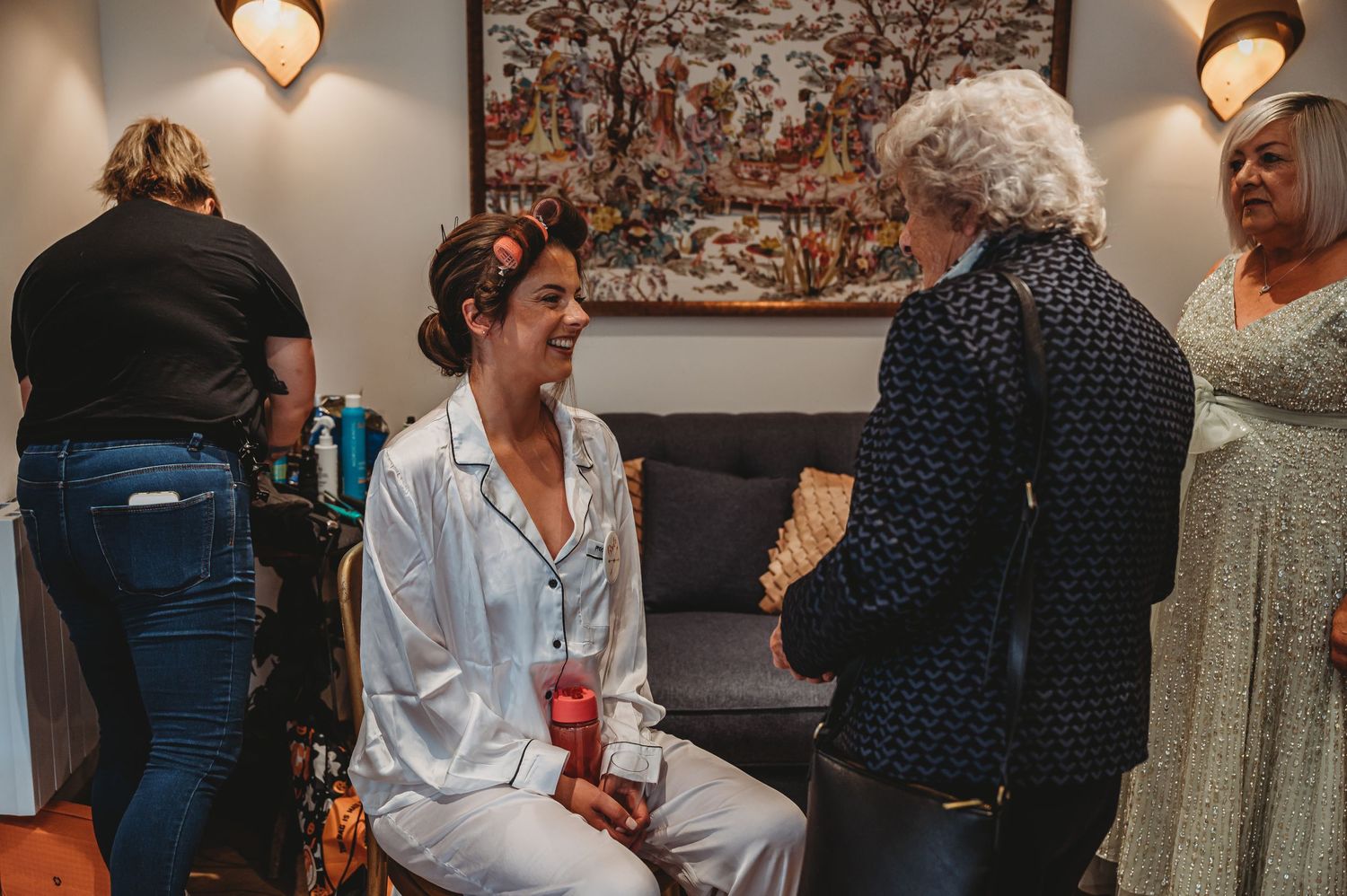 A gathering of people having a conversation in a room with decorative wall art.