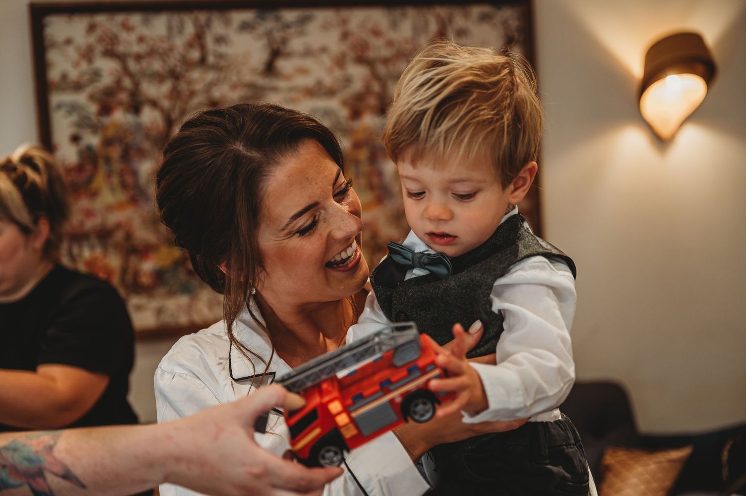 A young child examines a red toy violin while being held in warm indoor lighting.