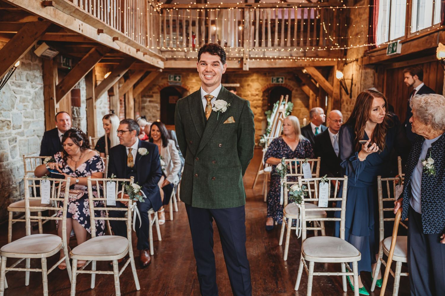 Wedding venue interior with wooden beams and white chairs set for ceremony.