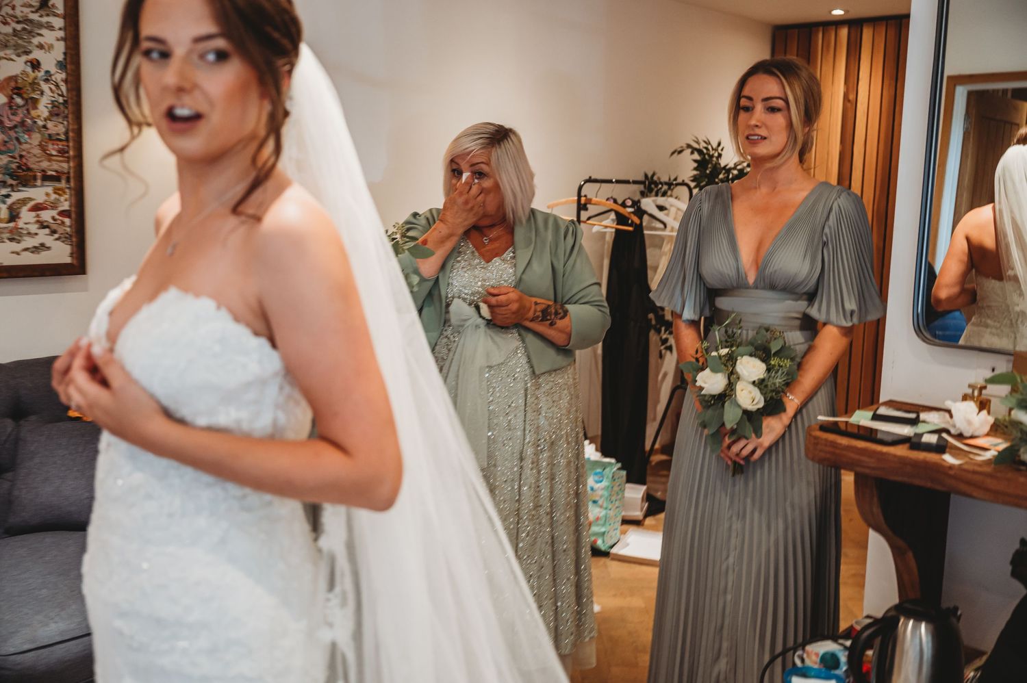Bridal preparation scene with elegant white wedding dress and gray bridesmaid gowns.