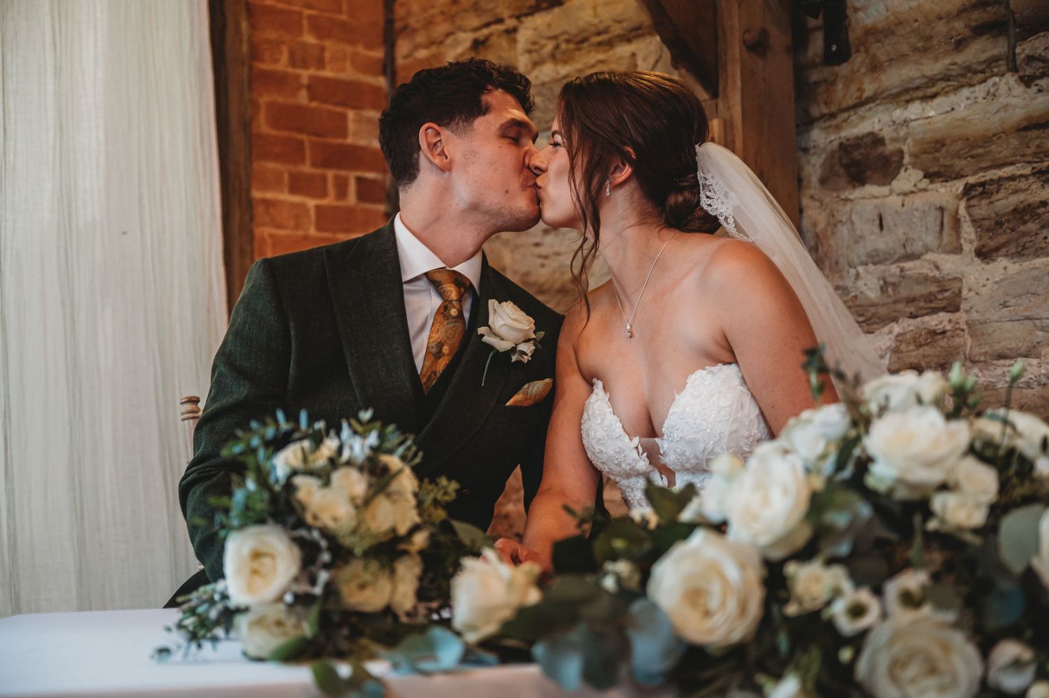 Romantic moment at wedding reception with white floral arrangements on table.