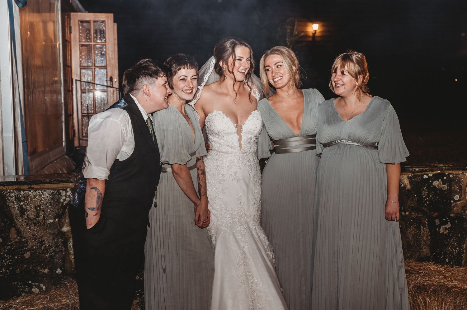 Wedding party poses together outdoors at night in coordinating grey formal attire.