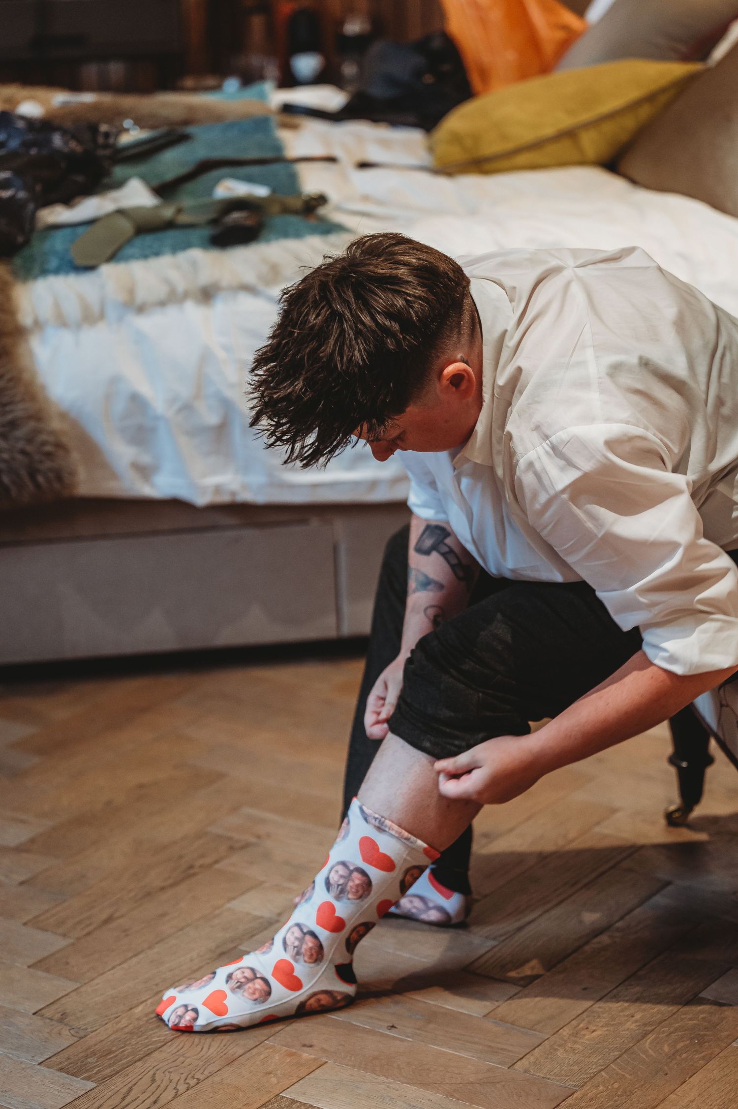 Person in white shirt sitting on floor putting on colorful patterned socks before an event.