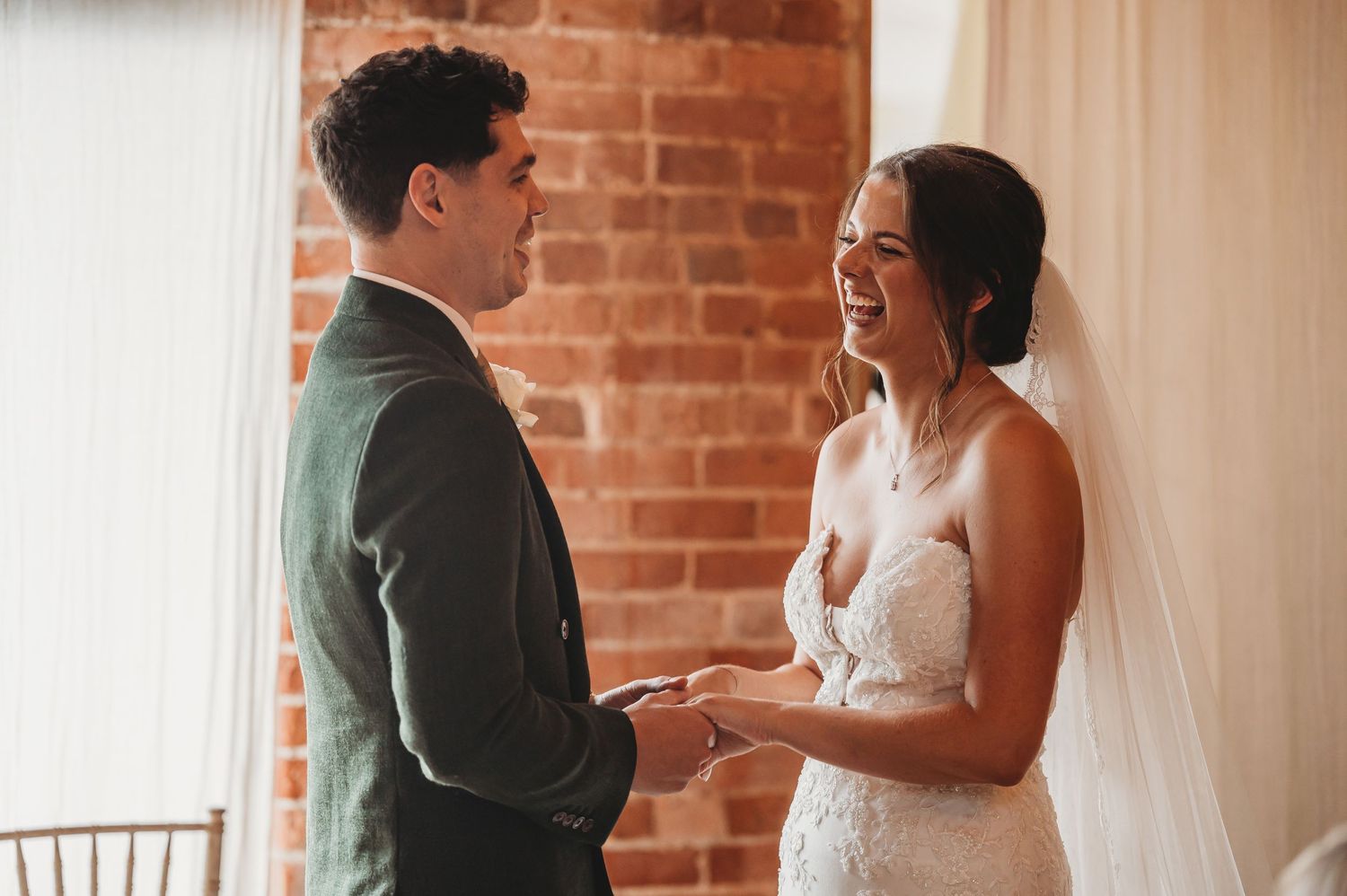 An intimate wedding ceremony where a couple exchanges vows in front of a rustic brick backdrop.