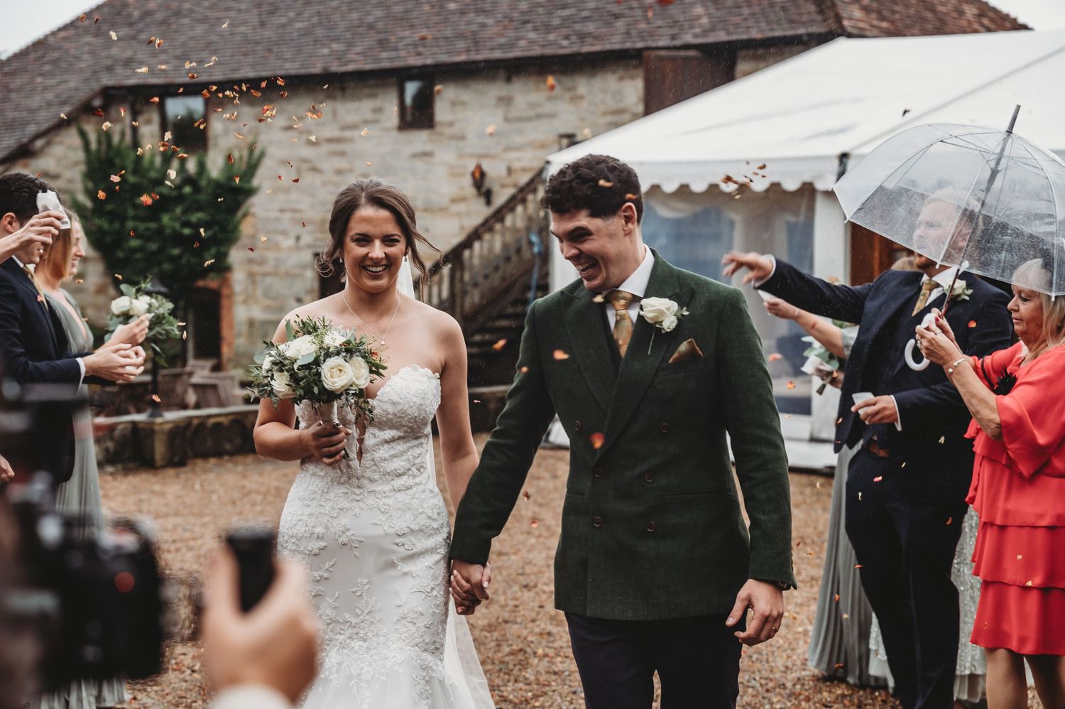 Wedding couple shares happy moment while walking past guests at countryside celebration.