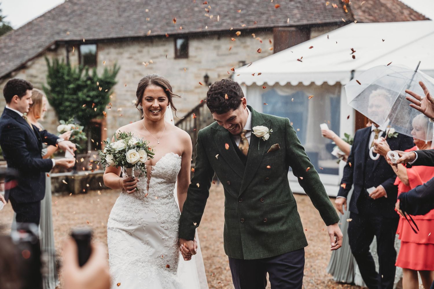 Candid moment of newlyweds laughing while walking through guest celebration at stone venue.