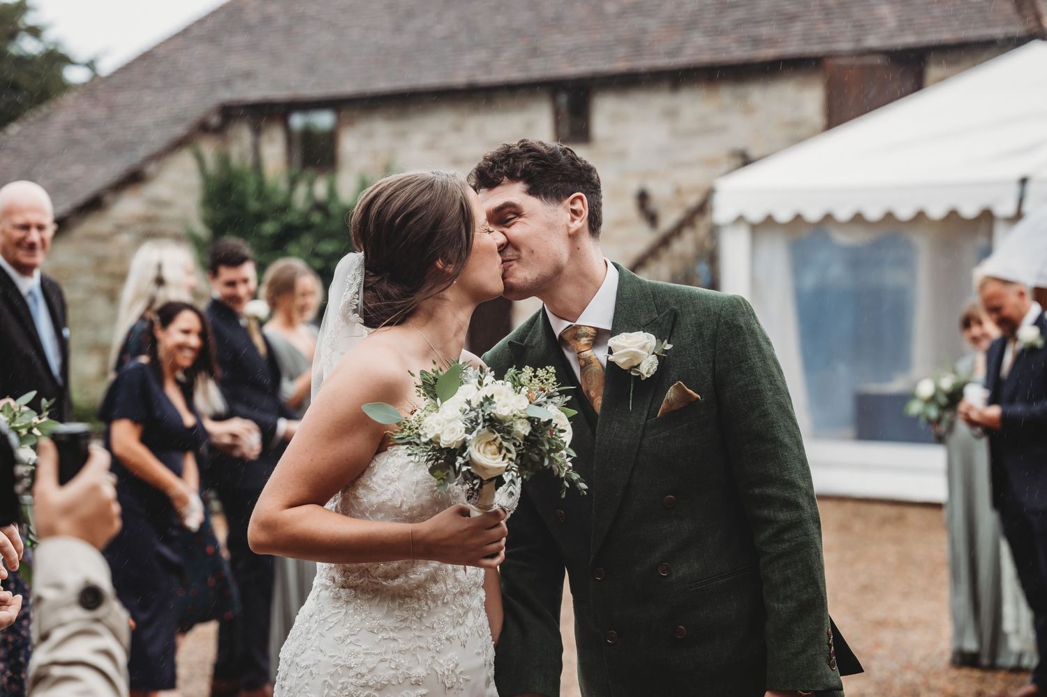 A joyful wedding celebration moment outside a rustic stone building with guests looking on.