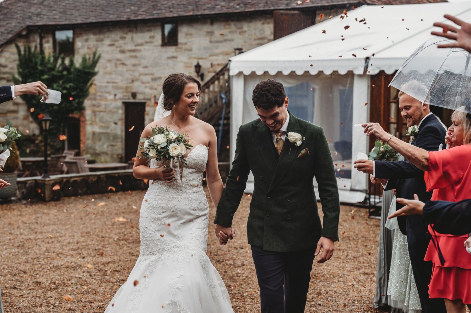 Couple celebrates their wedding day walking past guests at rustic outdoor venue.