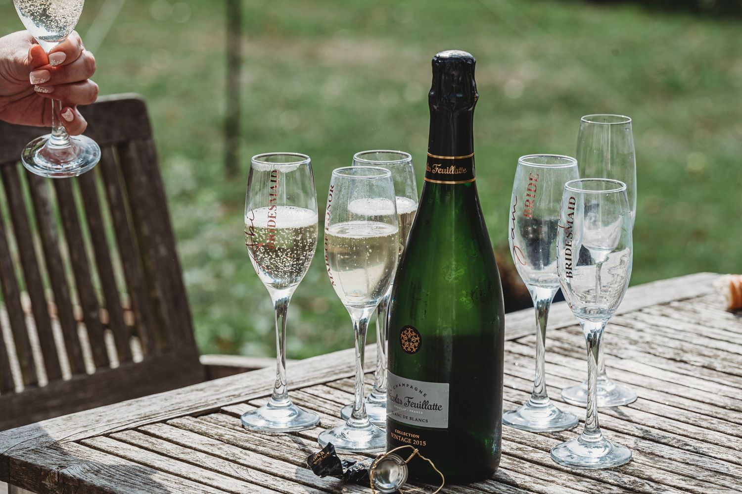 Champagne bottle and crystal flutes arranged on wooden outdoor table for celebration.