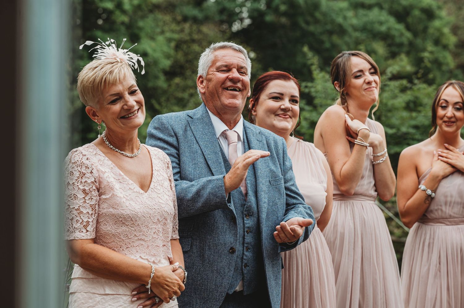 People dressed in formal attire share joyful laughter together during a special outdoor wedding celebration event.