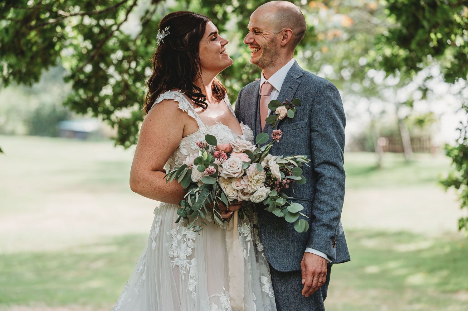 A tender wedding moment between two people in a garden setting with a beautiful floral bouquet.