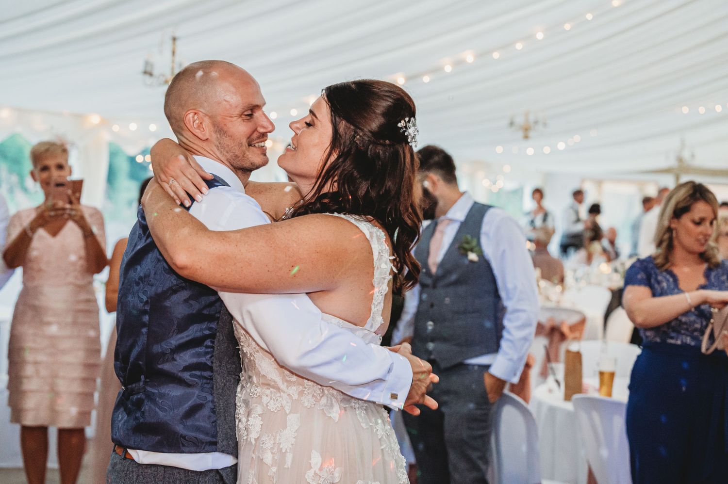 A couple shares a romantic dance together at a wedding reception under a white tent.