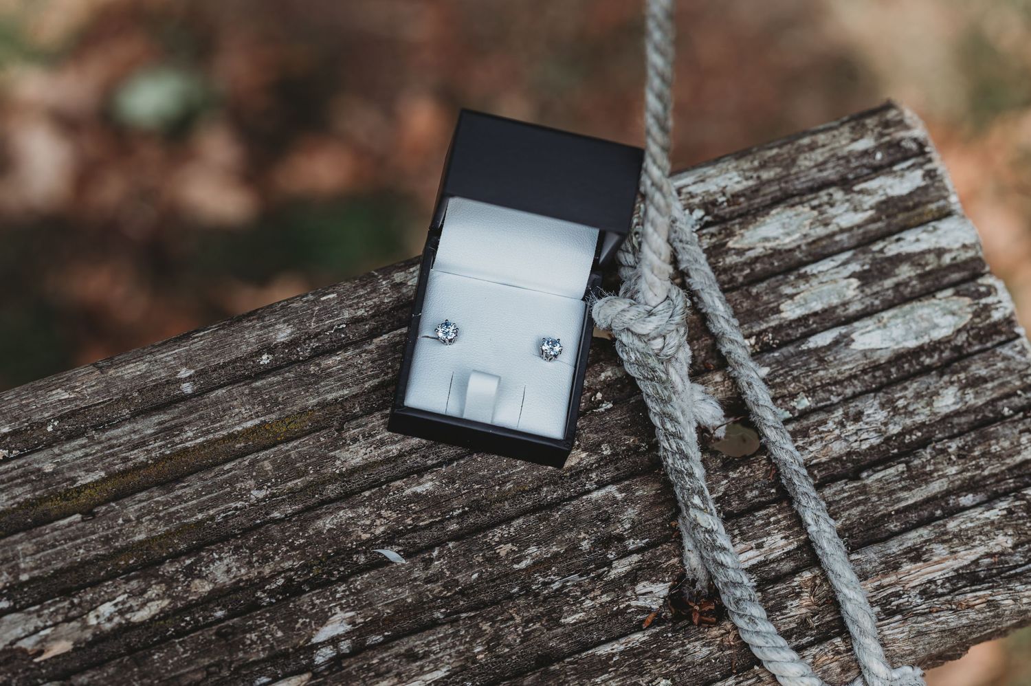 A black digital music player rests on weathered wood next to a gray braided cable.