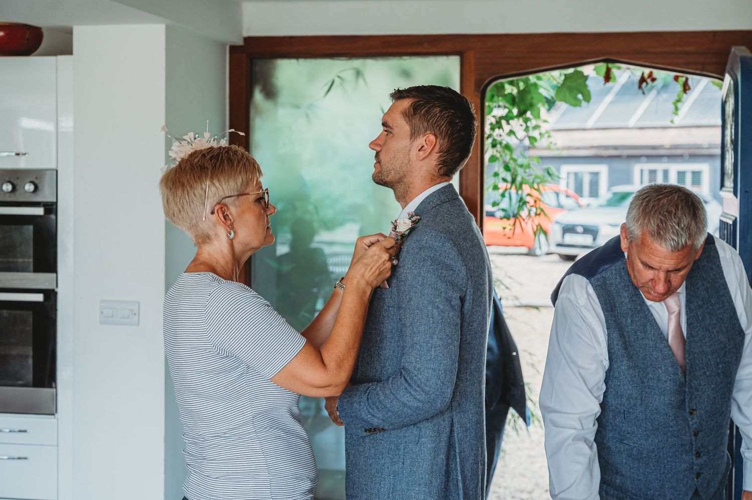 Final preparations in a modern kitchen as suited groomsmen prepare for a wedding ceremony.