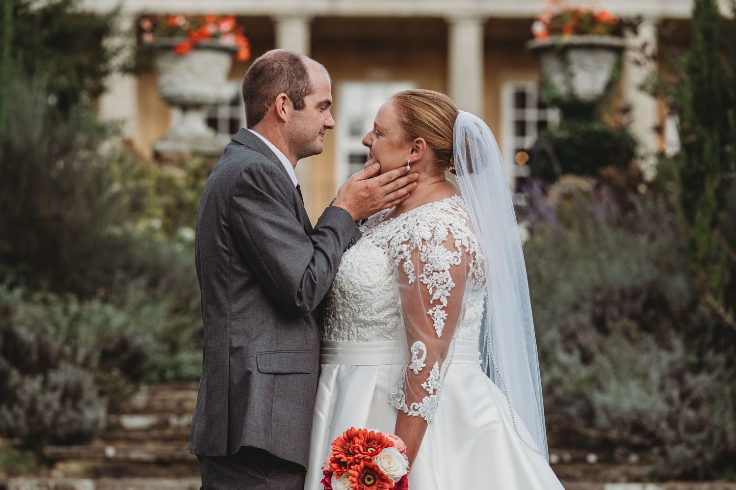 A wedding couple shares an intimate moment outdoors near a garden during their fall ceremony.