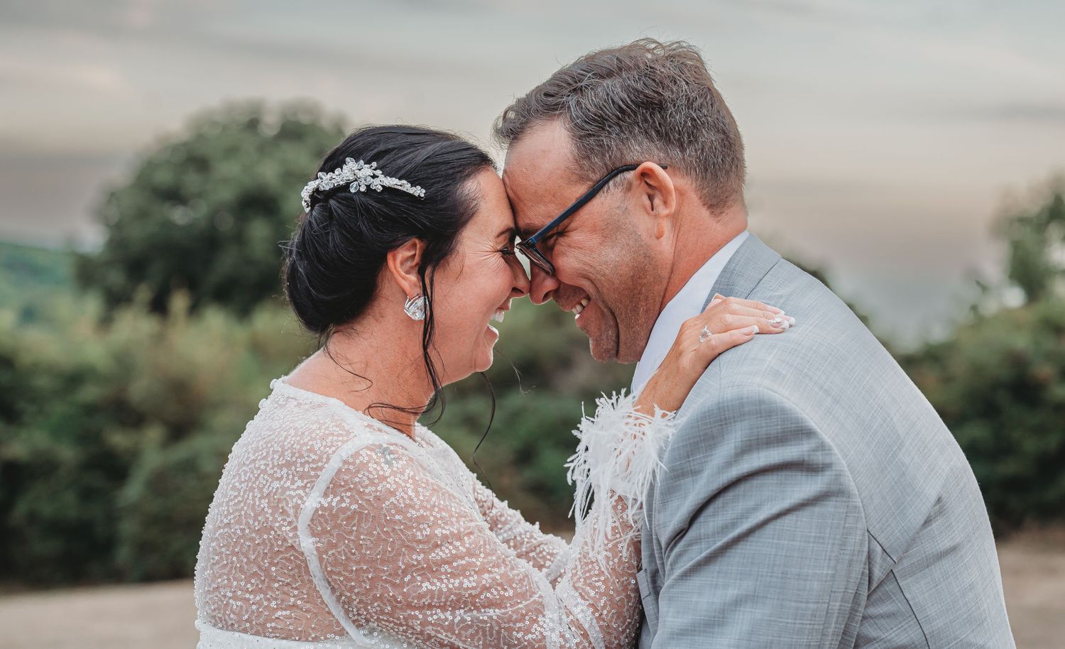 A romantic wedding couple shares an intimate moment outdoors in the soft evening light.