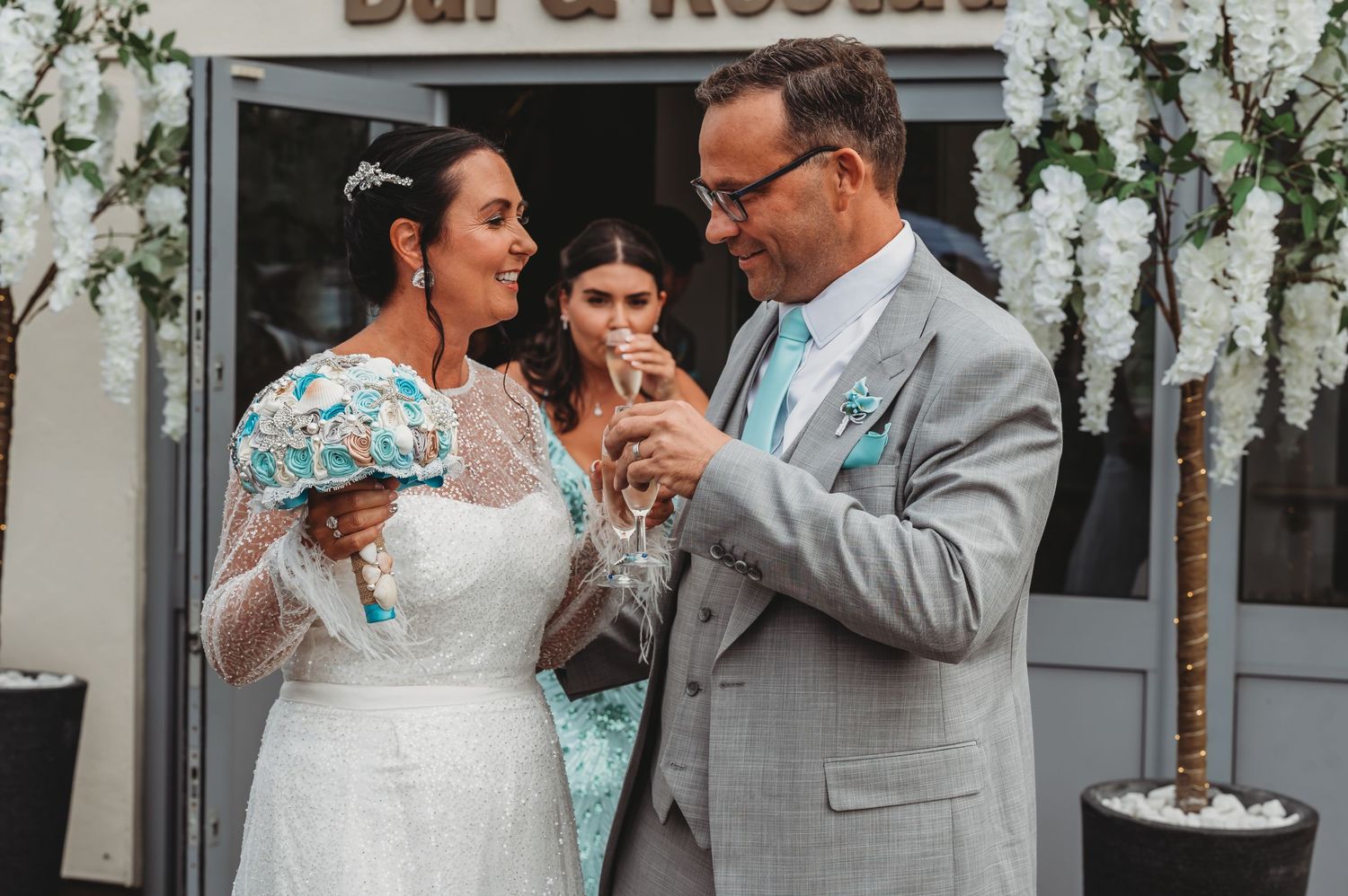 A couple shares a special moment while celebrating at their wedding ceremony in front of a white floral decorated venue.