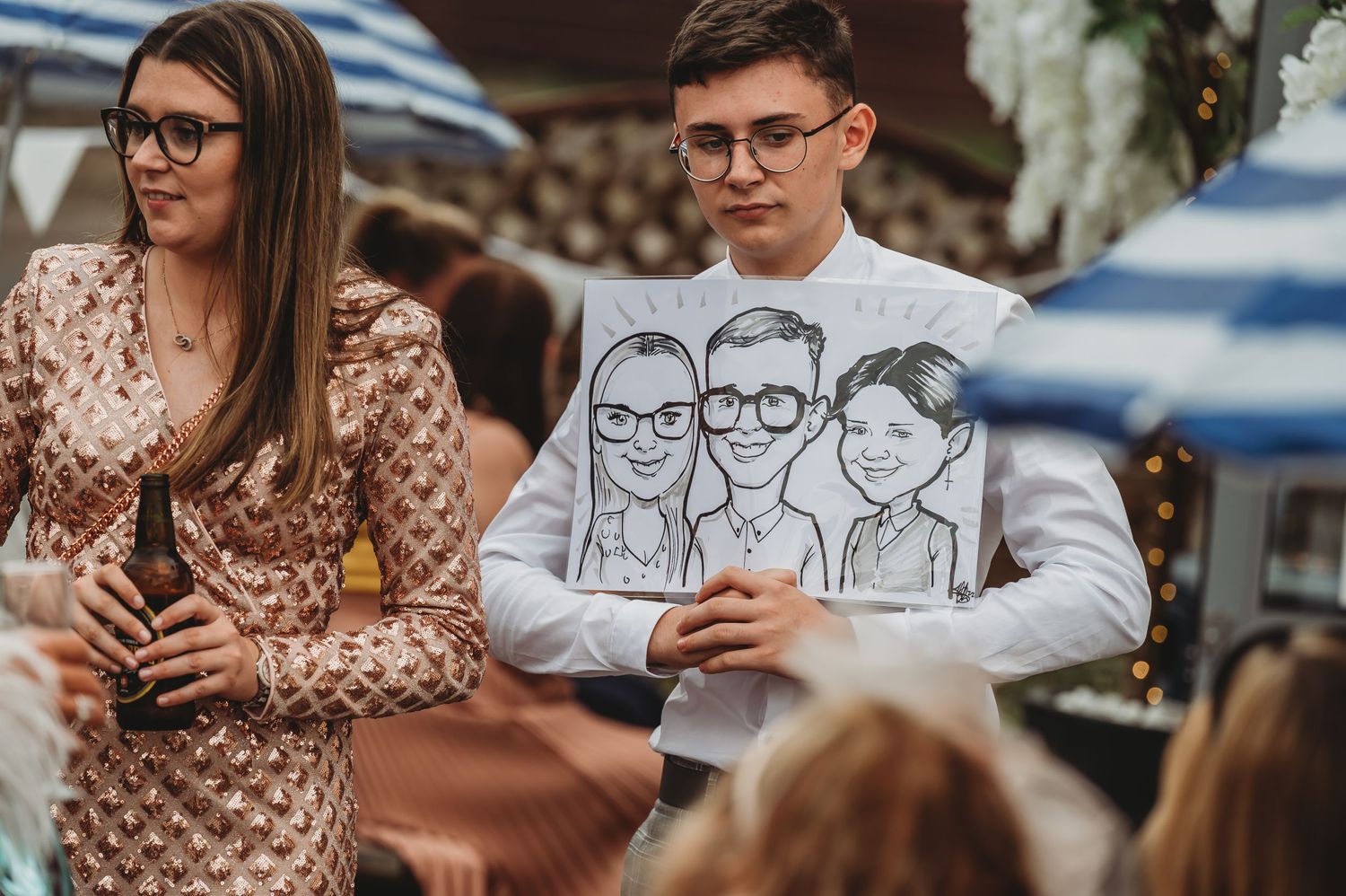 Person wearing glasses and a white sweatshirt with cartoon illustrations stands next to someone in a patterned dress.