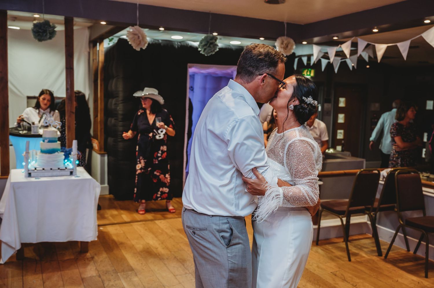 A couple shares their first dance at a wedding reception decorated with bunting and paper lanterns.