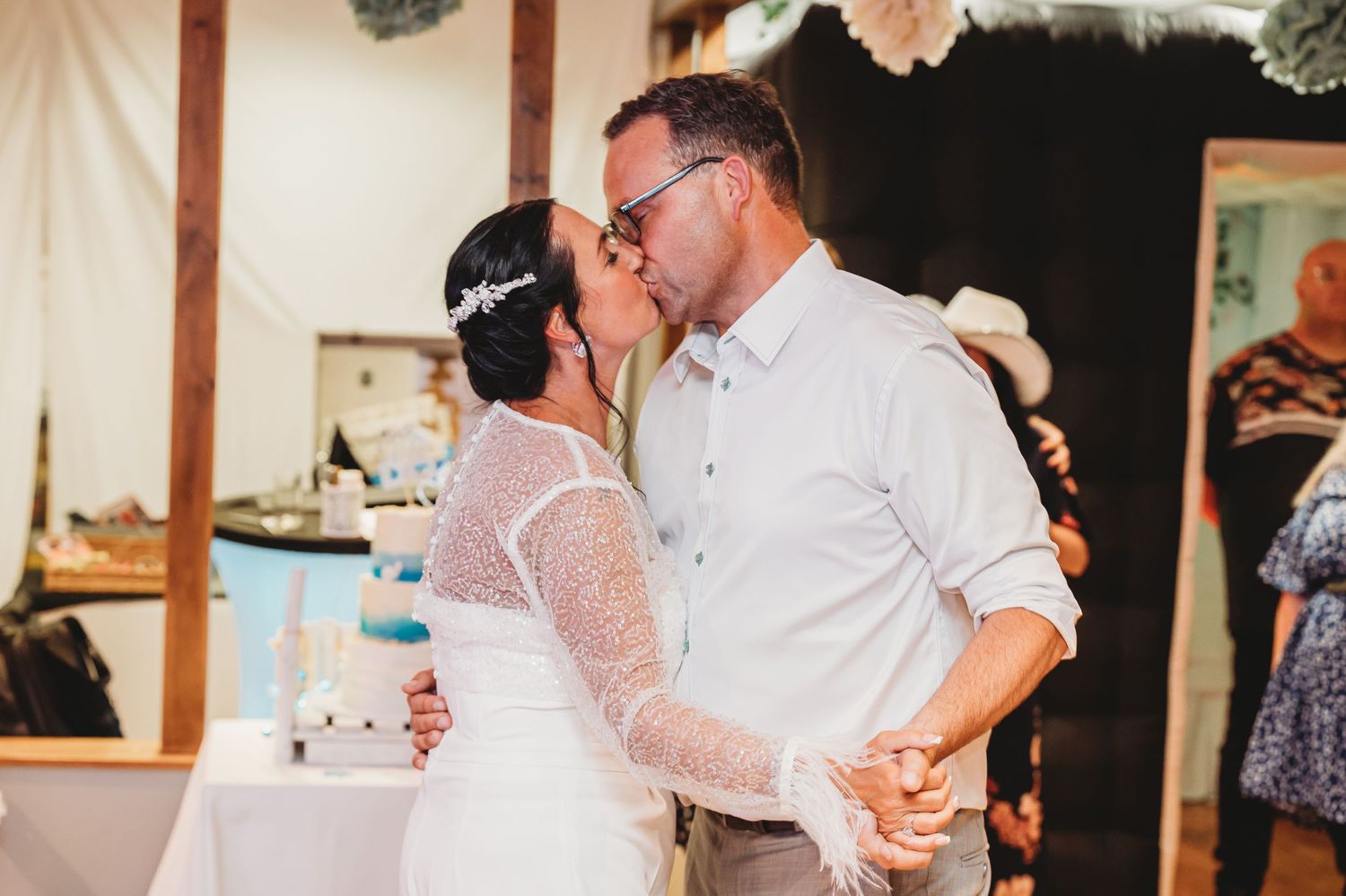 Couple shares an intimate dance together at an indoor wedding reception with a warm, candlelit atmosphere.