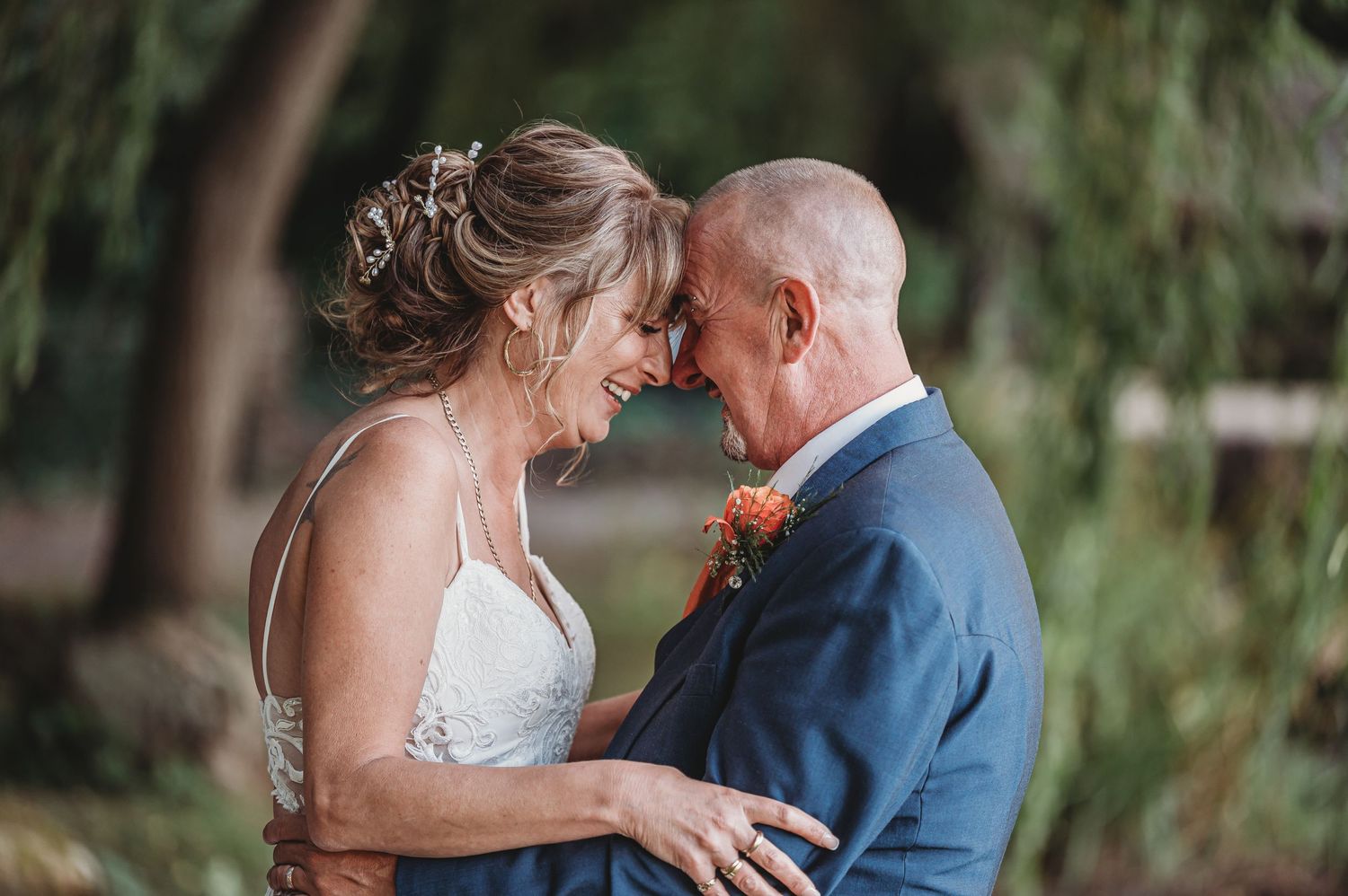 A romantic couple shares an intimate moment outdoors during their wedding celebration, with soft natural lighting.